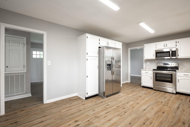kitchen with white cabinets, visible vents, stainless steel appliances, and light wood-type flooring