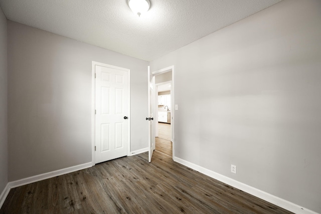unfurnished bedroom featuring dark wood-type flooring, baseboards, and a textured ceiling