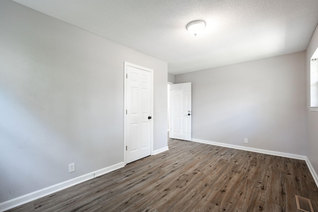 unfurnished room with baseboards, a textured ceiling, visible vents, and wood finished floors