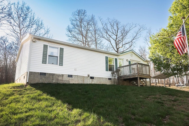 rear view of house featuring crawl space, a wooden deck, and a lawn