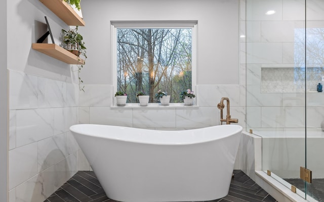 bathroom featuring tile walls, a stall shower, and a soaking tub
