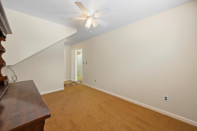 interior space featuring light colored carpet, ceiling fan, and baseboards