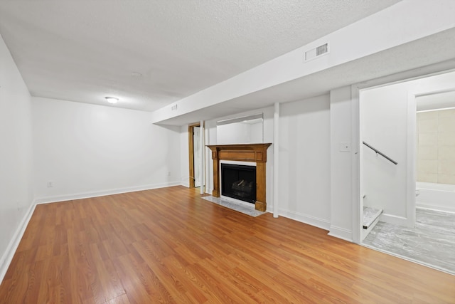 9027 Wooten Rd, Chattanooga, TN 37416 - unfurnished living room with a textured ceiling, light wood-type flooring, a fireplace with flush hearth, baseboards, and visible vents