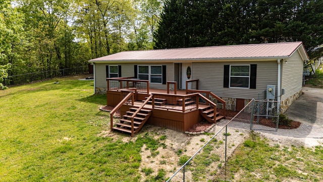 back of property featuring a deck, a yard, metal roof, and fence