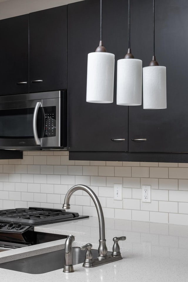 200 Manufacturers Rd Apt 428, Chattanooga, TN 37405 - kitchen view of dark cabinets, stainless steel microwave, decorative backsplash, and decorative light fixtures