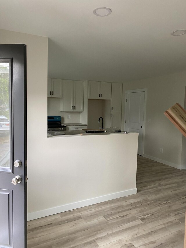 kitchen featuring baseboards, light wood-style floors, and electric range