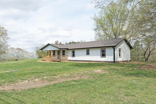 single story home featuring roof with shingles, a deck, and a front lawn