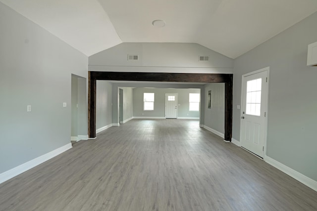 unfurnished living room featuring visible vents, baseboards, vaulted ceiling, and wood finished floors