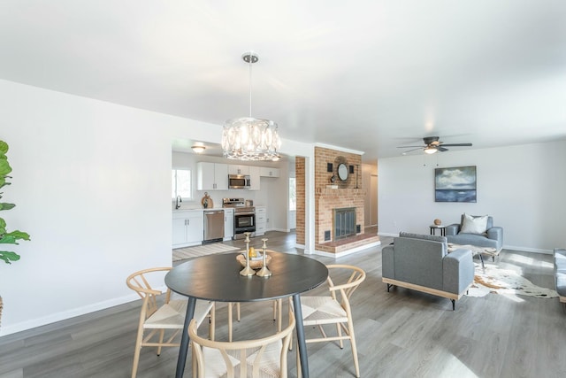 2041 Linwood Cir, Soddy Daisy, TN 37379 - dining area featuring ceiling fan with notable chandelier, light wood finished floors, a fireplace, and baseboards