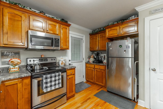 901 Haggard Rd, Ringgold, GA 30736 - kitchen with appliances with stainless steel finishes, ornamental molding, light wood-style floors, brown cabinets, and dark countertops