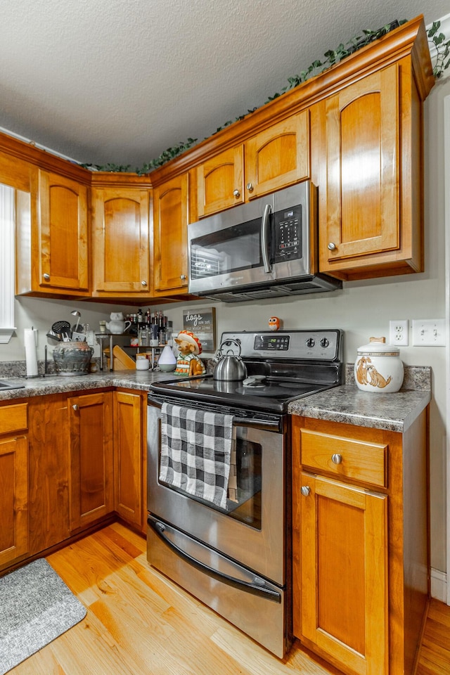 901 Haggard Rd, Ringgold, GA 30736 - kitchen with appliances with stainless steel finishes, brown cabinets, light wood-style flooring, a textured ceiling, and dark countertops