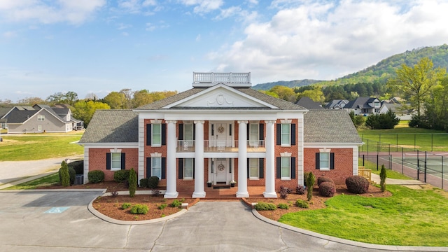 view of front of house featuring brick siding, a front yard, a porch, and fence