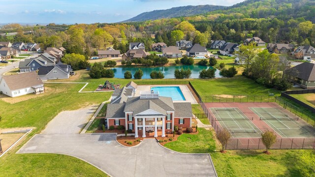 drone / aerial view featuring a wooded view, a residential view, and a water view