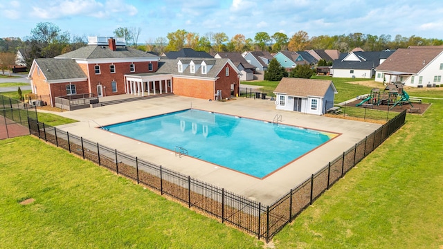 view of pool with a yard, fence, a patio, and a residential view