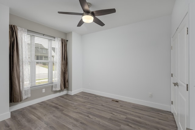 unfurnished room with wood finished floors, baseboards, a ceiling fan, and visible vents