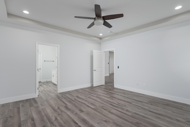 unfurnished bedroom with baseboards, recessed lighting, connected bathroom, and wood finished floors