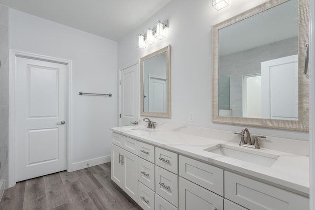 full bathroom featuring double vanity, baseboards, a sink, and wood finished floors