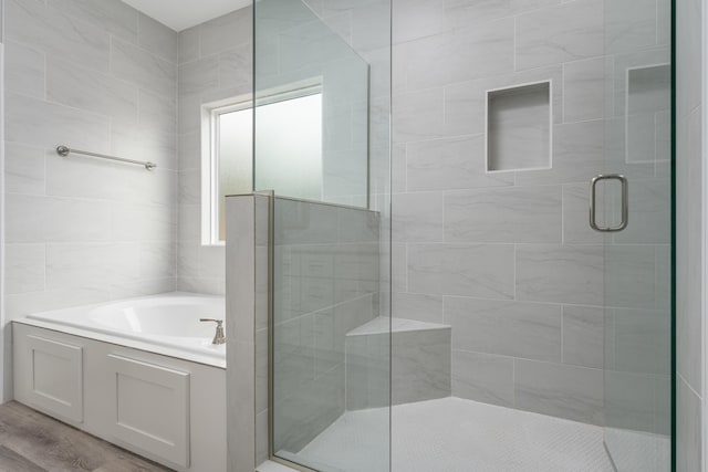 bathroom with a bath, a stall shower, and wood finished floors