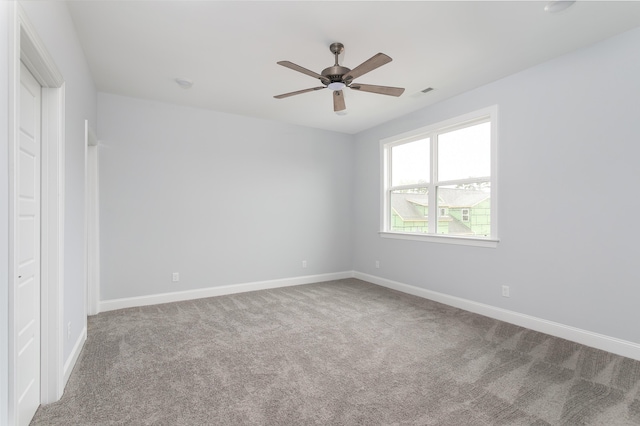 spare room with carpet flooring, visible vents, baseboards, and ceiling fan