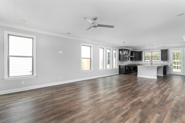 unfurnished living room featuring dark wood-type flooring, ornamental molding, ceiling fan, and baseboards