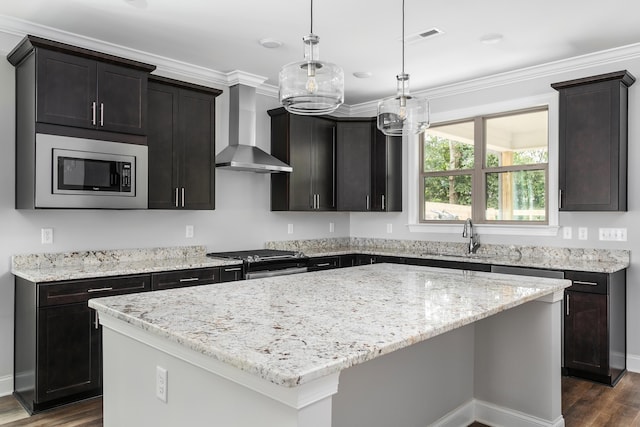kitchen featuring a center island, a sink, wall chimney range hood, dark wood finished floors, and stainless steel appliances