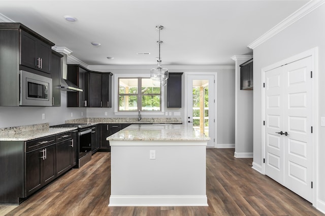 kitchen with a sink, ornamental molding, appliances with stainless steel finishes, light stone countertops, and a kitchen island