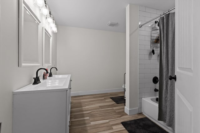 bathroom featuring vanity, baseboards, shower / bath combo, visible vents, and wood finished floors