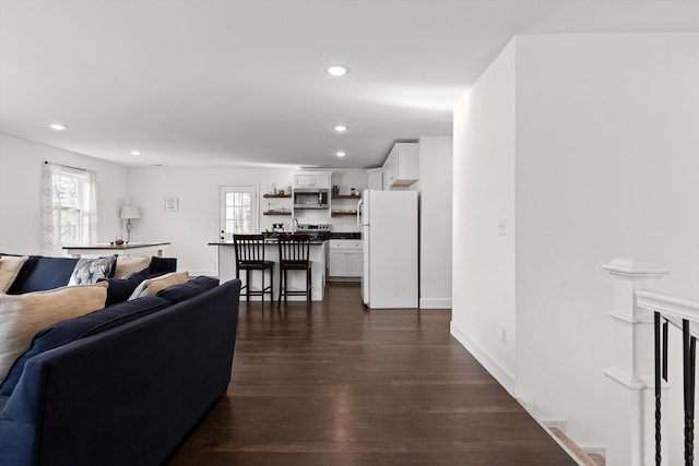 living area featuring dark wood-type flooring, baseboards, and recessed lighting