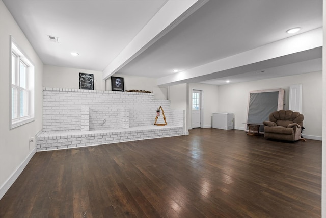 basement with dark wood-style flooring, baseboards, and visible vents