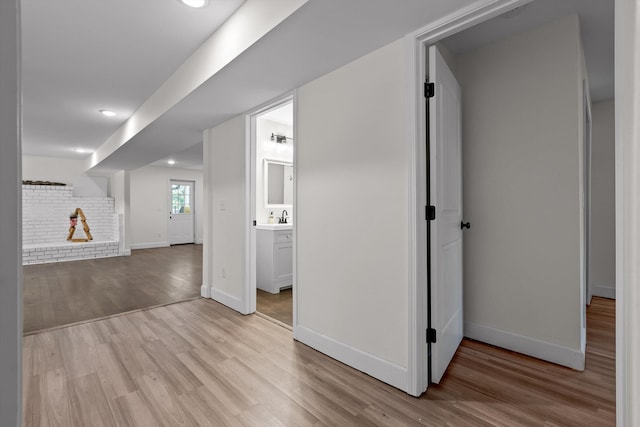 below grade area with recessed lighting, baseboards, a sink, and wood finished floors