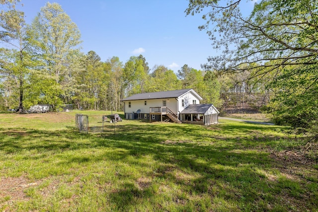 view of yard with a forest view, a wooden deck, and stairway