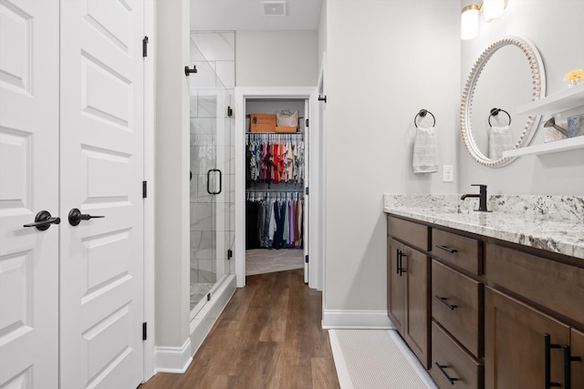 full bath featuring baseboards, visible vents, a shower stall, vanity, and a walk in closet