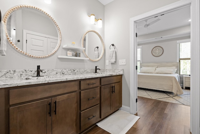 bathroom with double vanity, ensuite bath, wood finished floors, and a sink