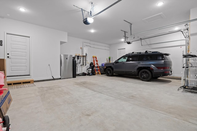 garage featuring freestanding refrigerator, a garage door opener, and recessed lighting