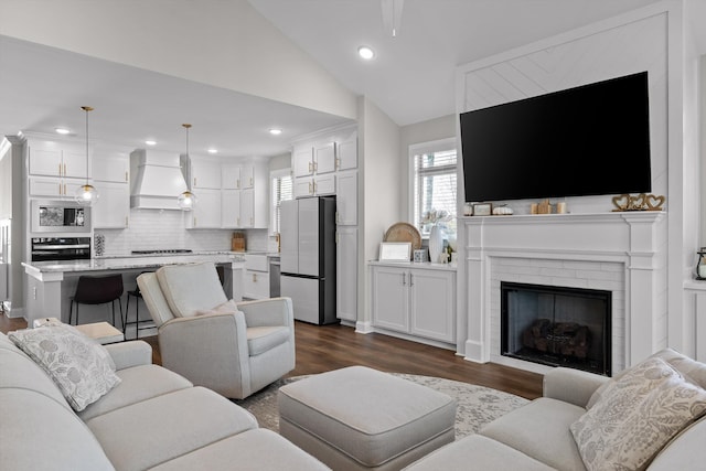 living room with lofted ceiling, recessed lighting, a healthy amount of sunlight, and dark wood finished floors