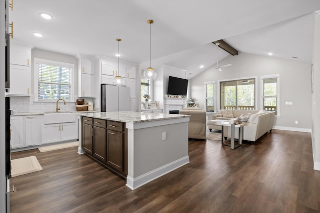 kitchen featuring a sink, freestanding refrigerator, open floor plan, and dark wood-type flooring