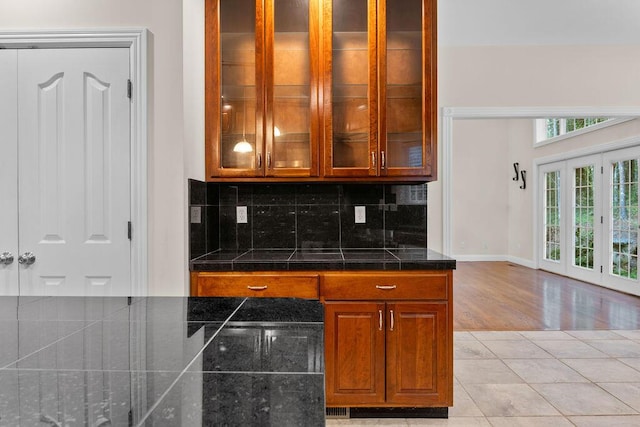 7111 River Run Dr, Chattanooga, TN 37416 - kitchen with tasteful backsplash, baseboards, light tile patterned floors, glass insert cabinets, and brown cabinetry