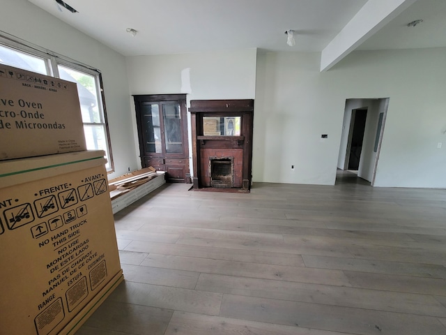 unfurnished living room with a fireplace with flush hearth and wood finished floors