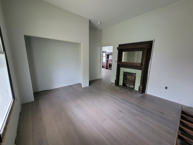 unfurnished living room featuring a stone fireplace and wood finished floors