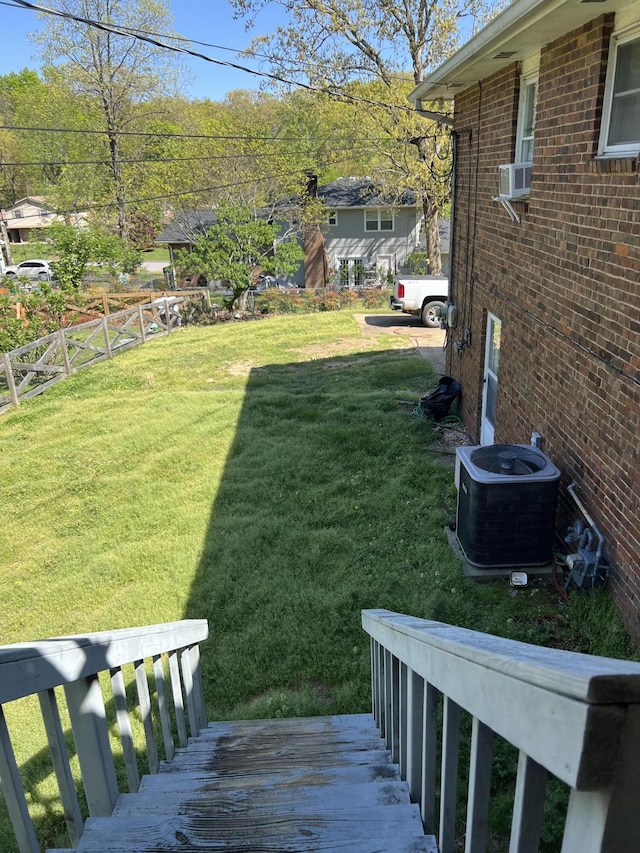 view of yard featuring central AC, fence, and cooling unit