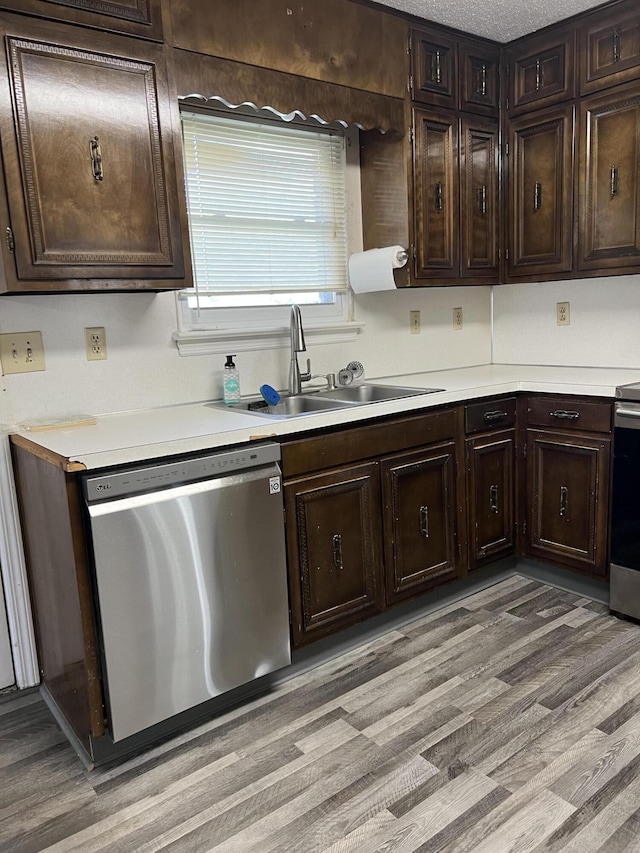 kitchen with light countertops, light wood-type flooring, appliances with stainless steel finishes, and a sink