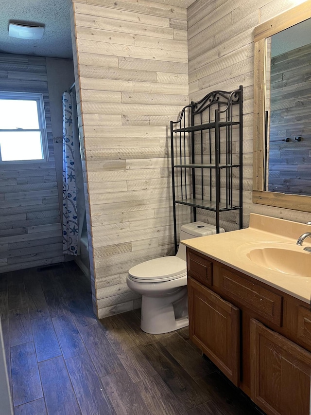 bathroom featuring wooden walls, toilet, hardwood / wood-style floors, and vanity