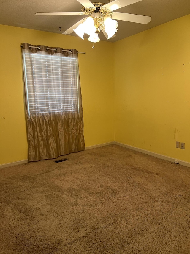 empty room featuring visible vents, baseboards, a ceiling fan, and carpet
