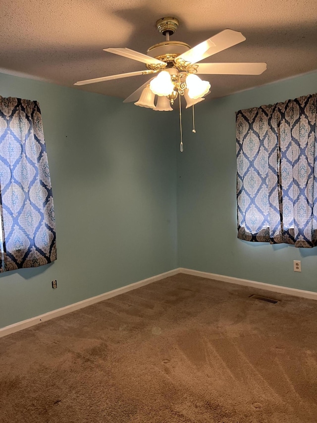 carpeted spare room with a textured ceiling, ceiling fan, baseboards, and visible vents