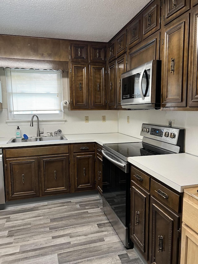 9121 Potomac Dr, Chattanooga, TN 37421 - kitchen with stainless steel appliances, a sink, light countertops, a textured ceiling, and dark brown cabinets