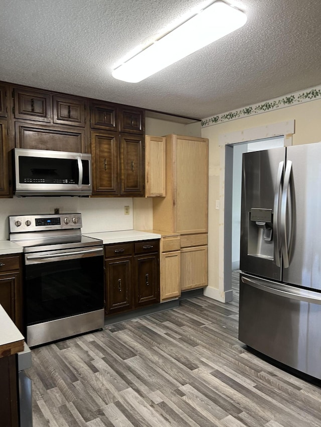 9121 Potomac Dr, Chattanooga, TN 37421 - kitchen with appliances with stainless steel finishes, light countertops, light wood-type flooring, a textured ceiling, and dark brown cabinetry