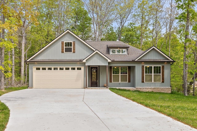 view of front facade with a garage, a front lawn, roof with shingles, and concrete driveway