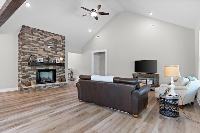 living area with visible vents, a ceiling fan, wood finished floors, a fireplace, and high vaulted ceiling