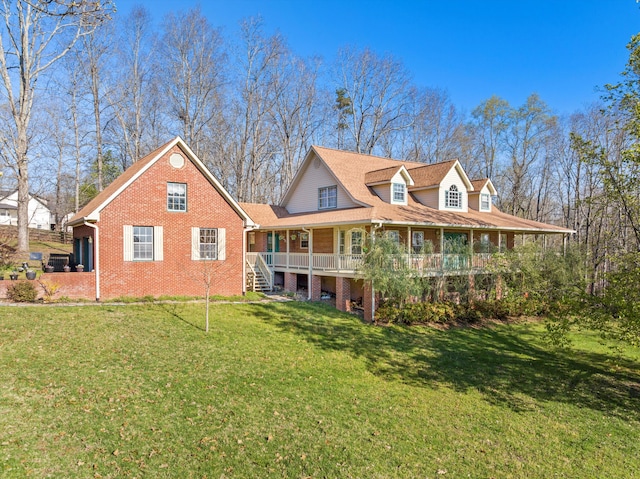 back of house featuring a yard, a porch, a shingled roof, and brick siding