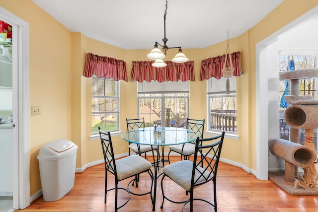 dining room featuring baseboards, light wood finished floors, and a chandelier